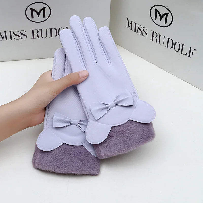 Light purple women's gloves with bow accents and furry cuffs held against Miss Rudolf branded boxes
