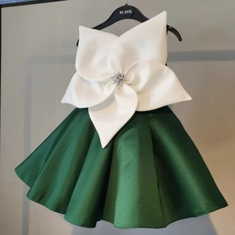 Green satin dress with large white flower embellishment and rhinestone center on hanger