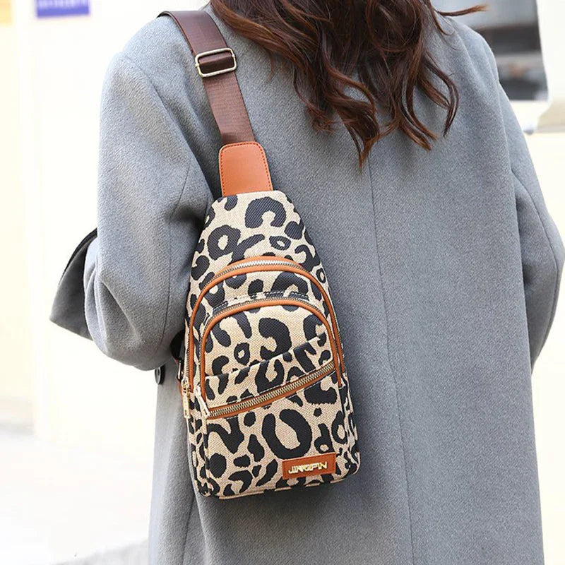 Woman wearing gray coat carrying leopard print sling backpack with brown straps and zippers