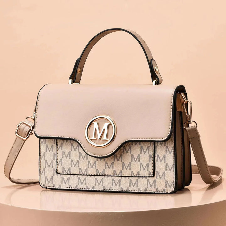 Beige and tan handbag with top handle, gold 'M' logo, and monogram pattern on front pocket