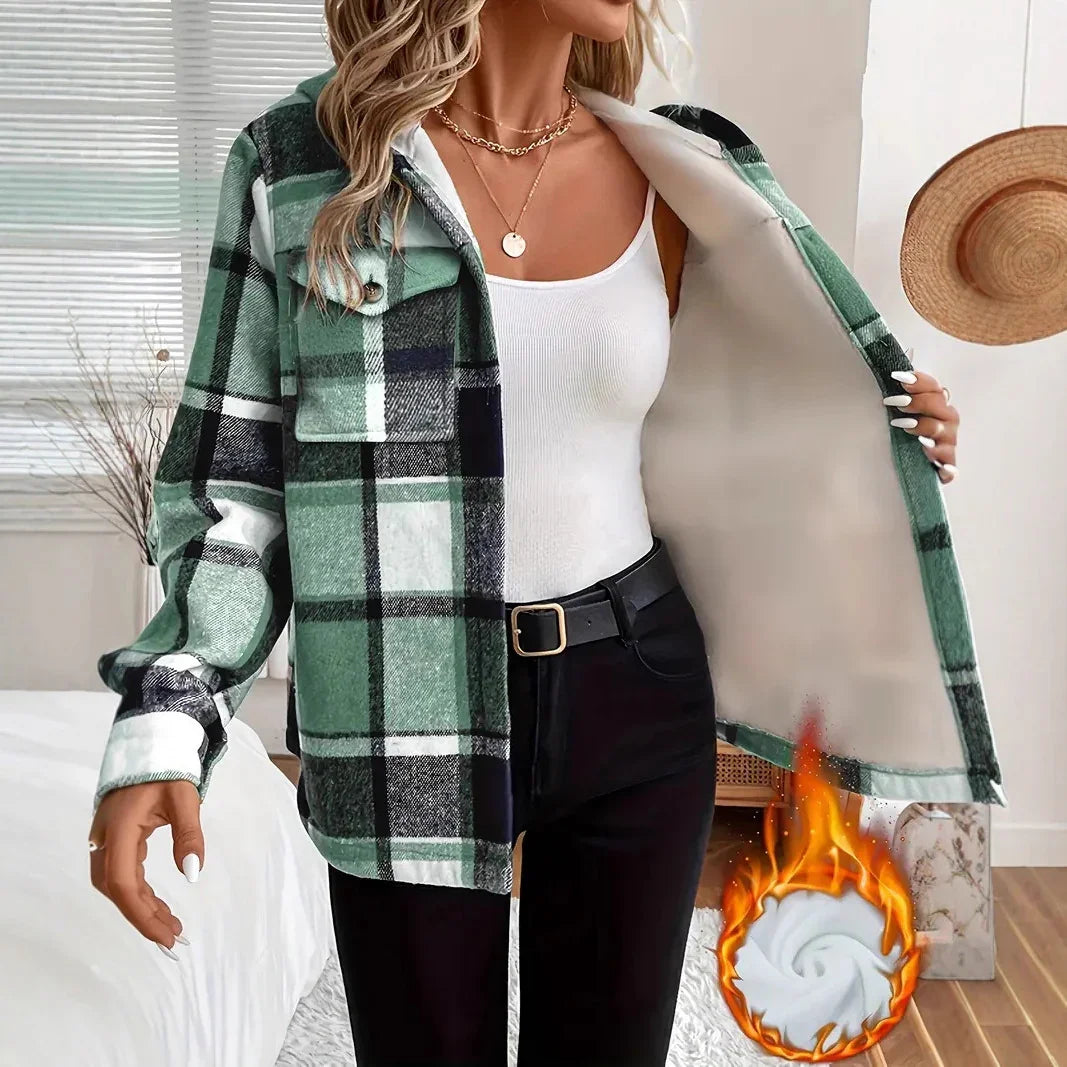 Woman wearing green plaid flannel jacket over white tank top and black pants in minimalist room