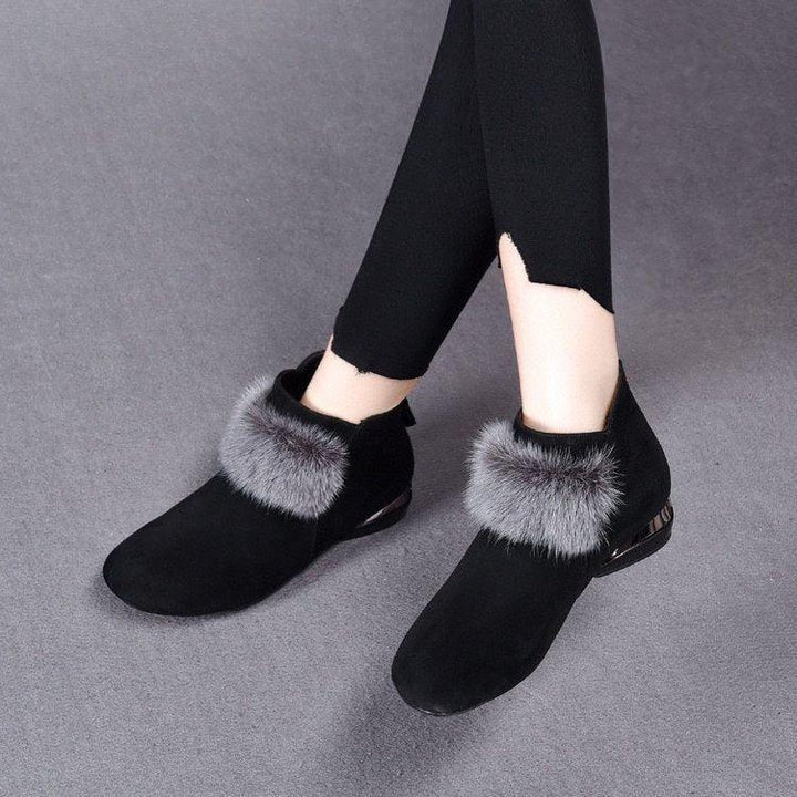 Black suede ankle boots with gray faux fur trim worn with black leggings on gray floor