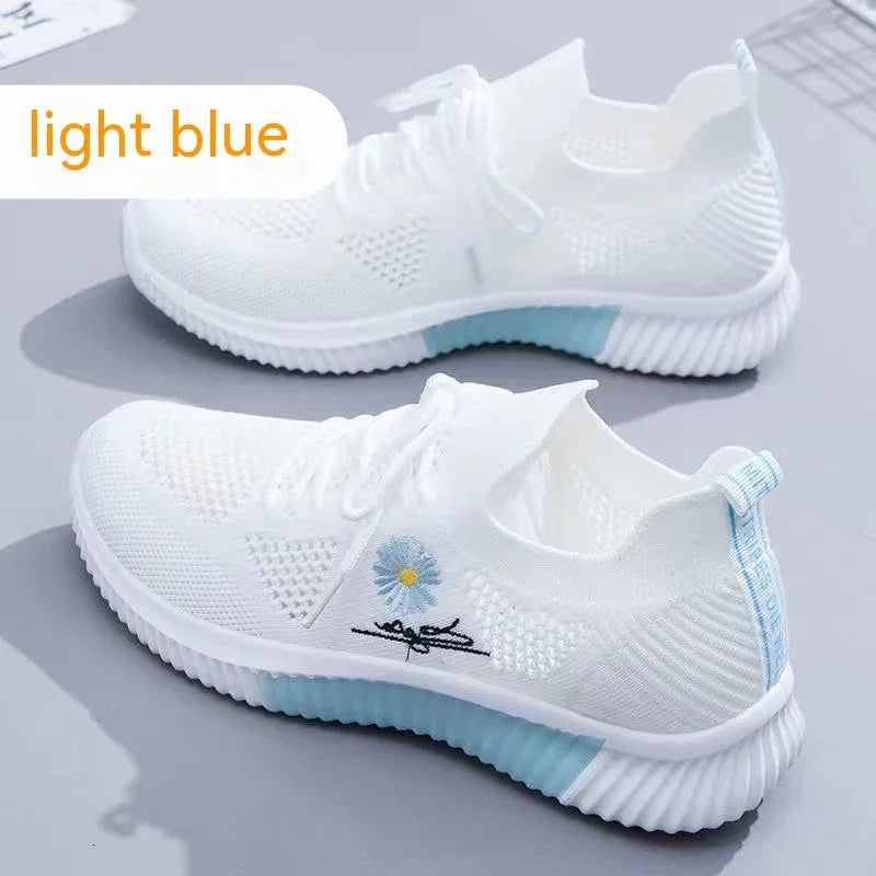 White knit sneakers with light blue soles and floral embroidery on side, light blue label at heel