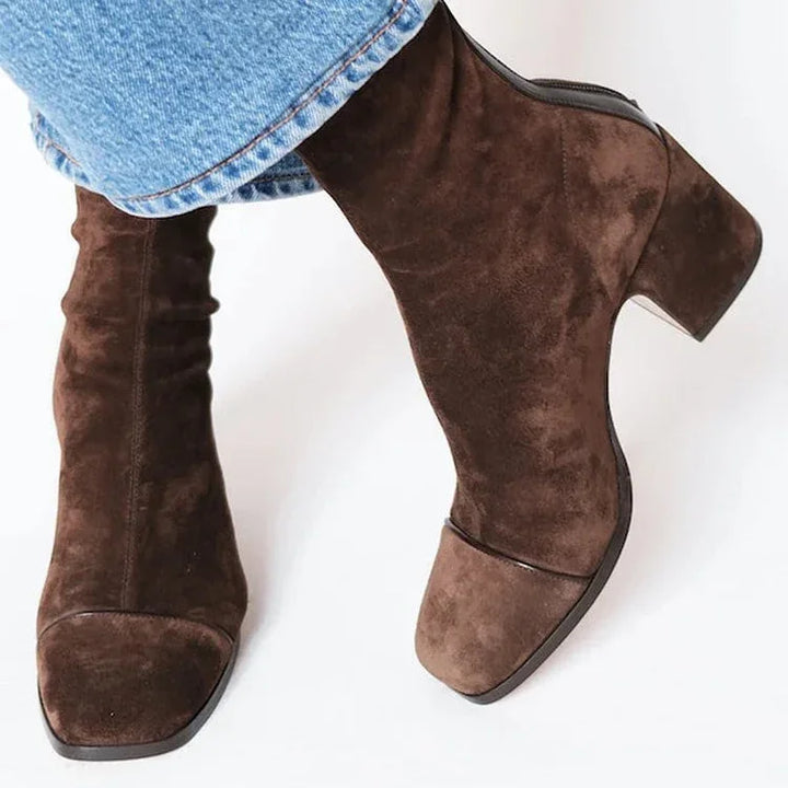 Brown suede ankle boots with block heels worn with blue denim jeans on white background
