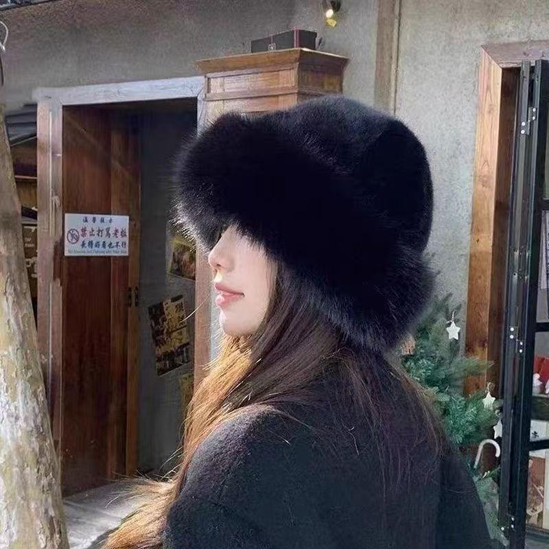 Woman wearing a large black fur hat and dark coat indoors with wooden furniture and Christmas tree