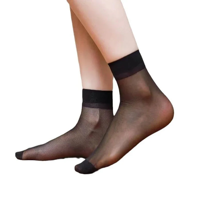 Pair of sheer black ankle socks on feet with reinforced toes and cuffs against white background
