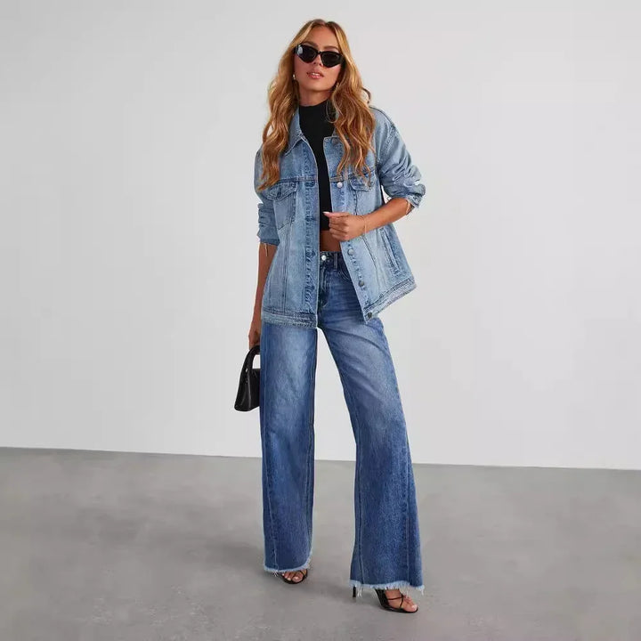 Woman wearing oversized light denim jacket and wide-leg jeans with black crop top and sunglasses
