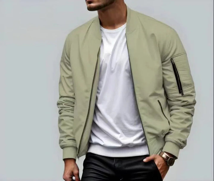 Man wearing beige bomber jacket with zippered pockets over white shirt and black pants