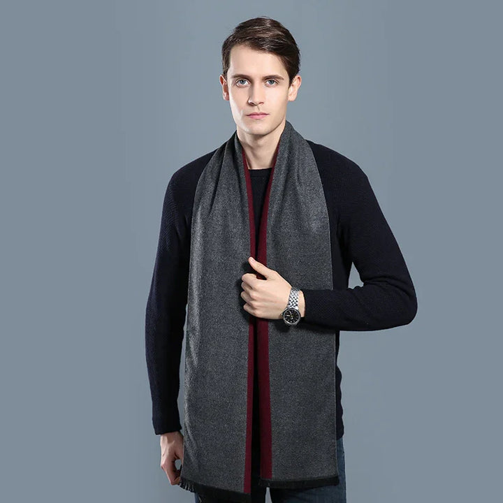 Young man wearing a dark gray and burgundy scarf with a black sweater against gray background