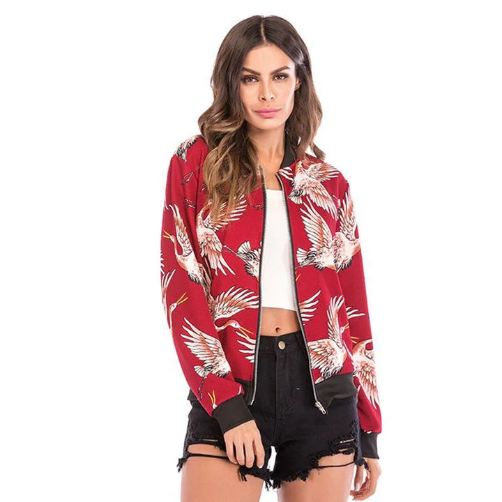 Woman wearing red bomber jacket with white crane bird print, paired with white crop top and black distressed shorts