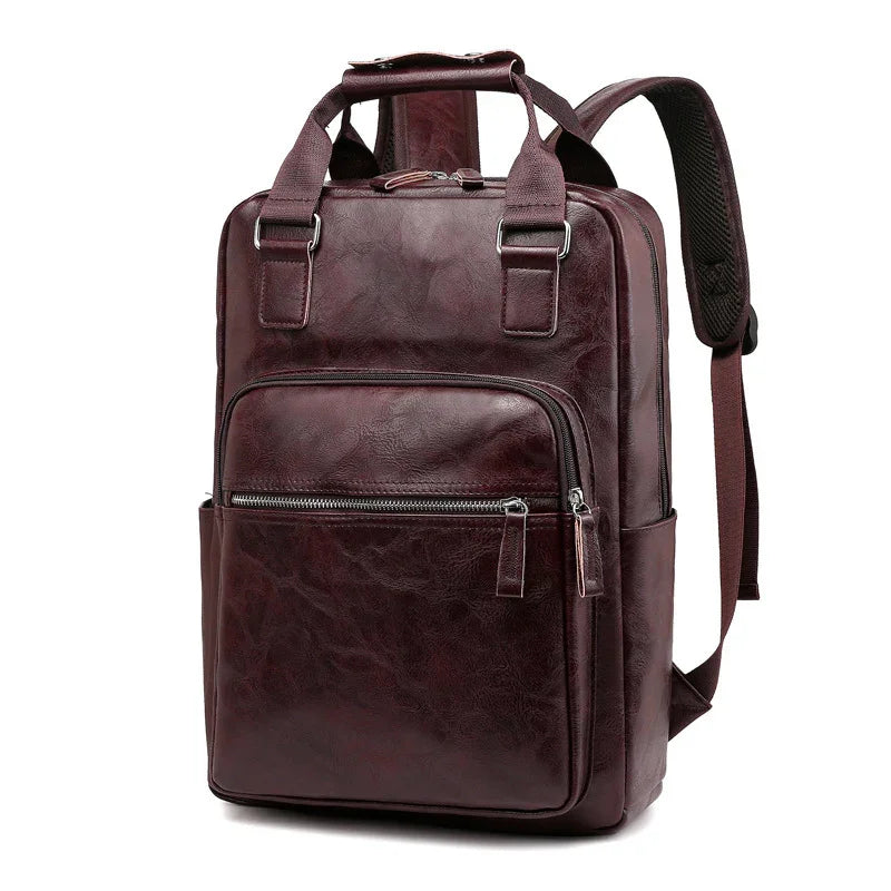 Brown leather backpack with front zip pocket, dual handles, and padded shoulder straps