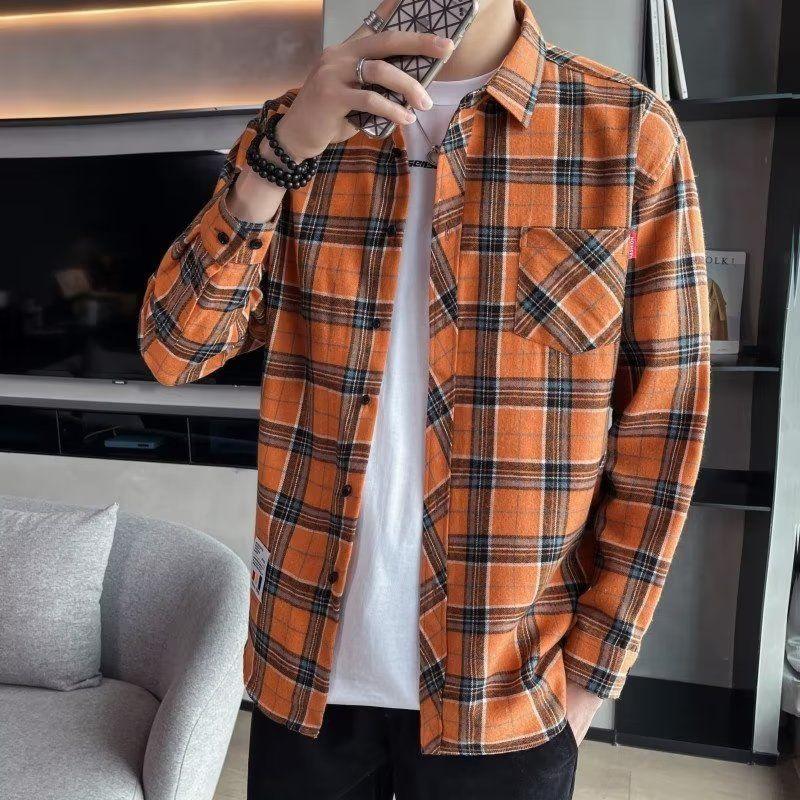 Man wearing orange and black plaid flannel shirt over white t-shirt in modern living room