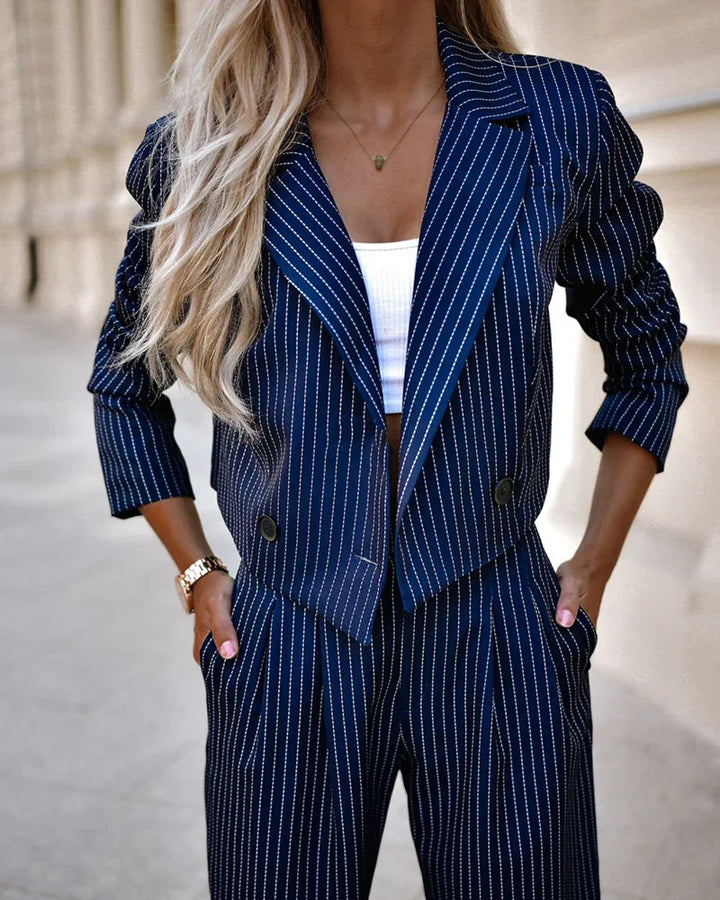 Woman wearing navy blue pinstripe blazer and matching tailored pants with hands in pockets