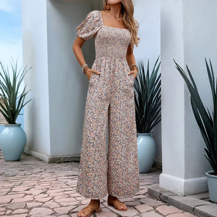 woman in floral print wide-leg jumpsuit with puff sleeves and square neckline on outdoor stone patio