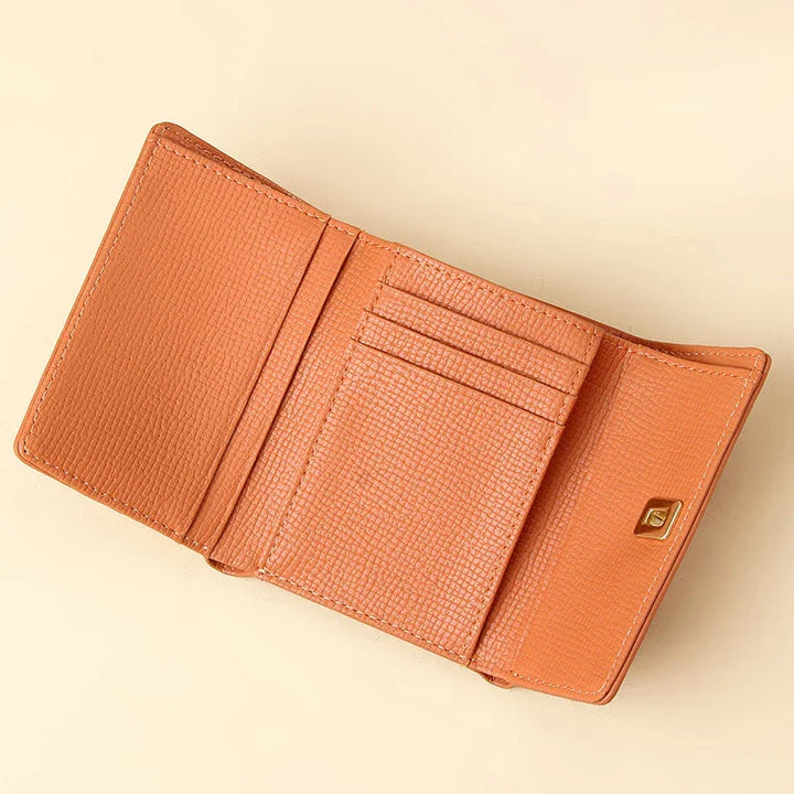 Open tan leather trifold wallet with textured surface and card slots on beige background