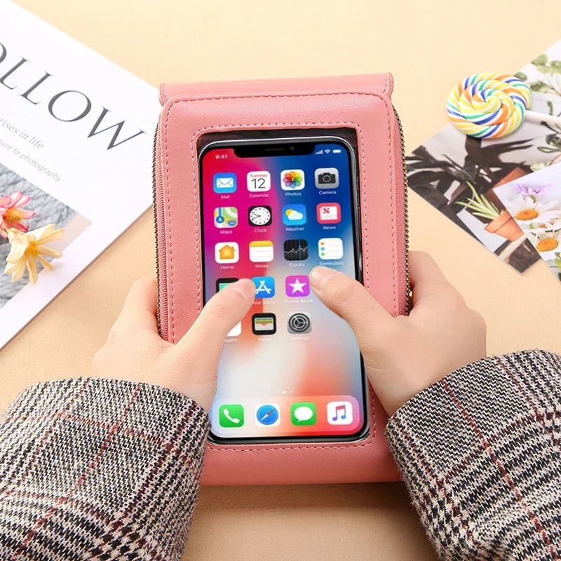 Hands holding pink phone pouch with touchscreen smartphone, plaid sleeves, lollipop and floral magazine