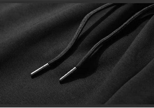 Close-up of black hoodie fabric with braided drawstrings and metal aglets