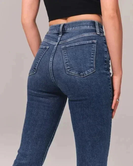 Back view of woman wearing high-waisted blue denim jeans with two back pockets and a black cropped top