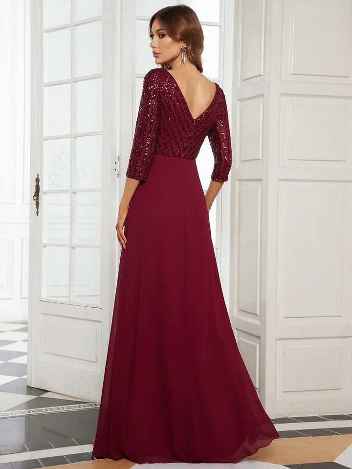 Woman in elegant burgundy evening gown with sequined top and deep V back in bright classic room