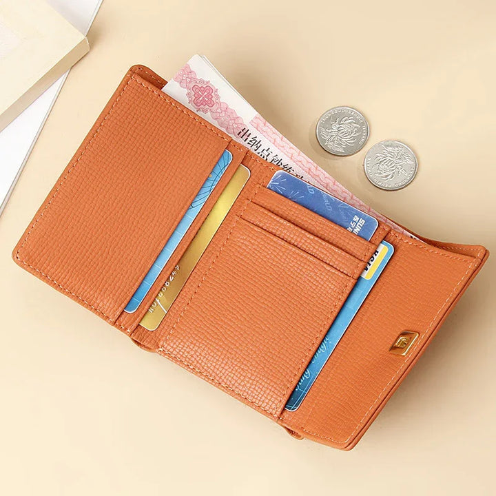 Orange textured leather wallet open showing cards, cash, and two coins on beige surface