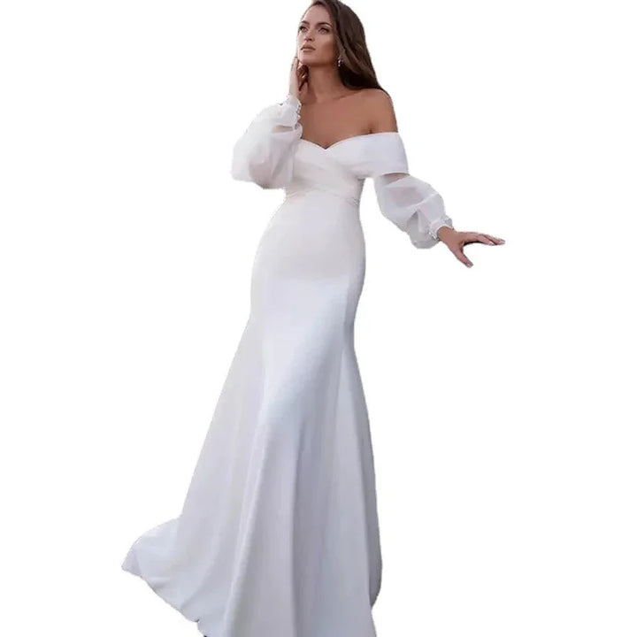Woman in elegant white off-shoulder long gown with sheer puff sleeves on white background