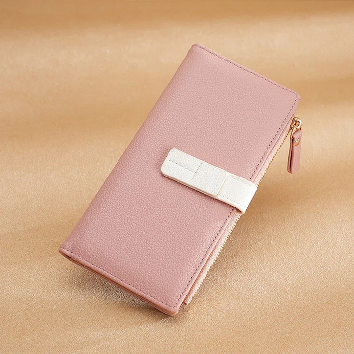 Pink leather wallet with white strap and zipper on beige background