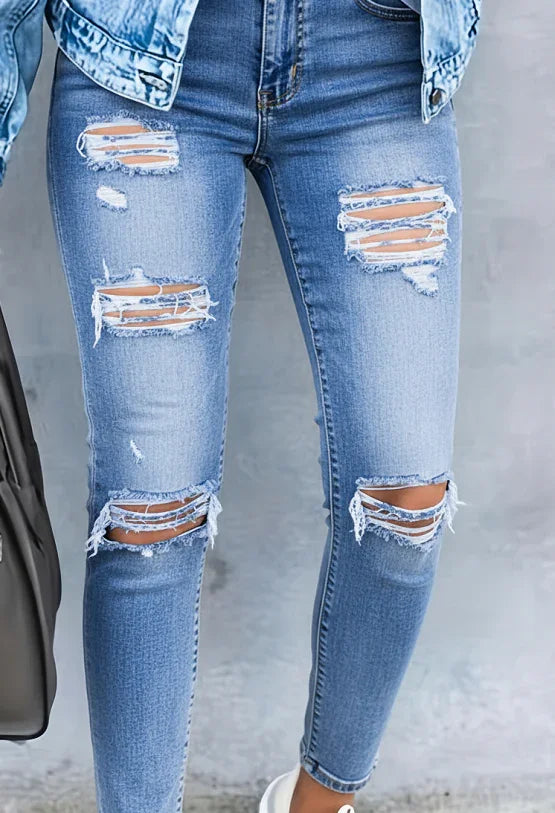 Close-up of legs wearing light blue distressed skinny jeans with rips and frayed details