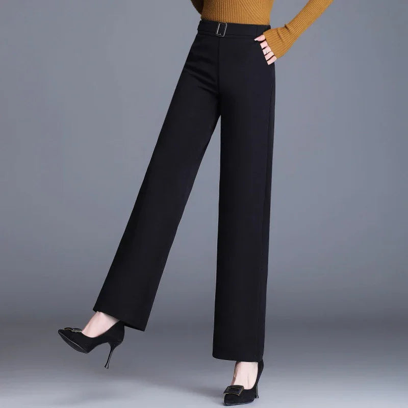 Woman wearing high-waisted black wide-leg pants with belt and black high heels