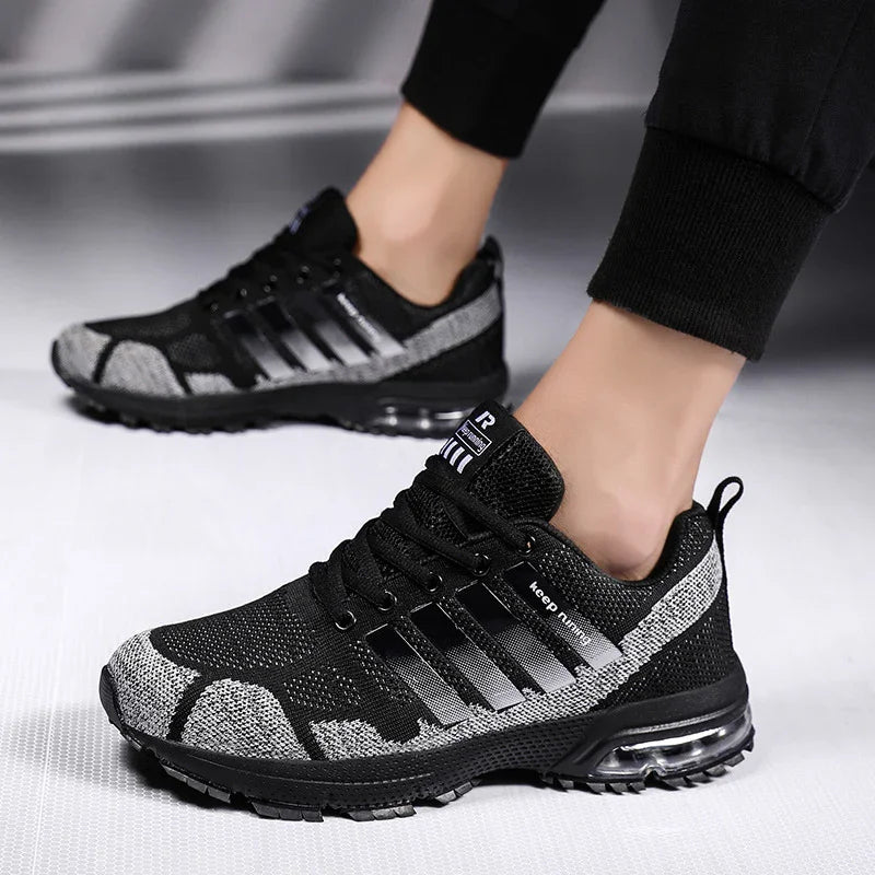 Black and gray athletic running shoes with air cushion sole worn by person in black pants