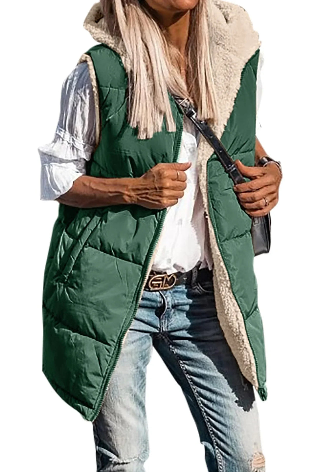 Woman wearing green quilted sleeveless vest with beige fleece lining over white blouse and ripped jeans