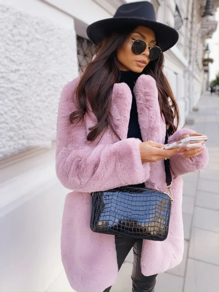 Woman in pink faux fur coat, black wide-brim hat, sunglasses, black crocodile handbag, using smartphone outdoors