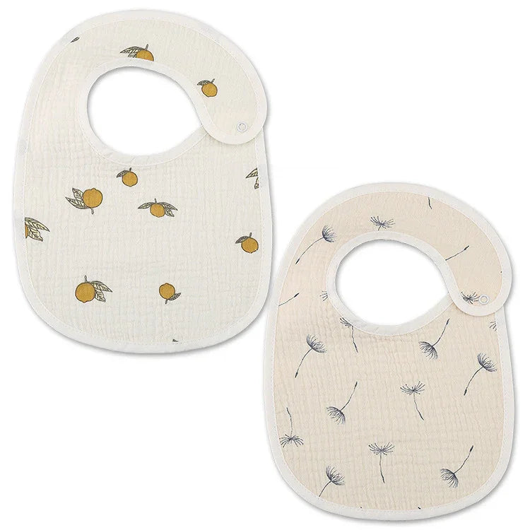 Two baby bibs with snap closures, one with orange fruit print, one with dandelion seed design