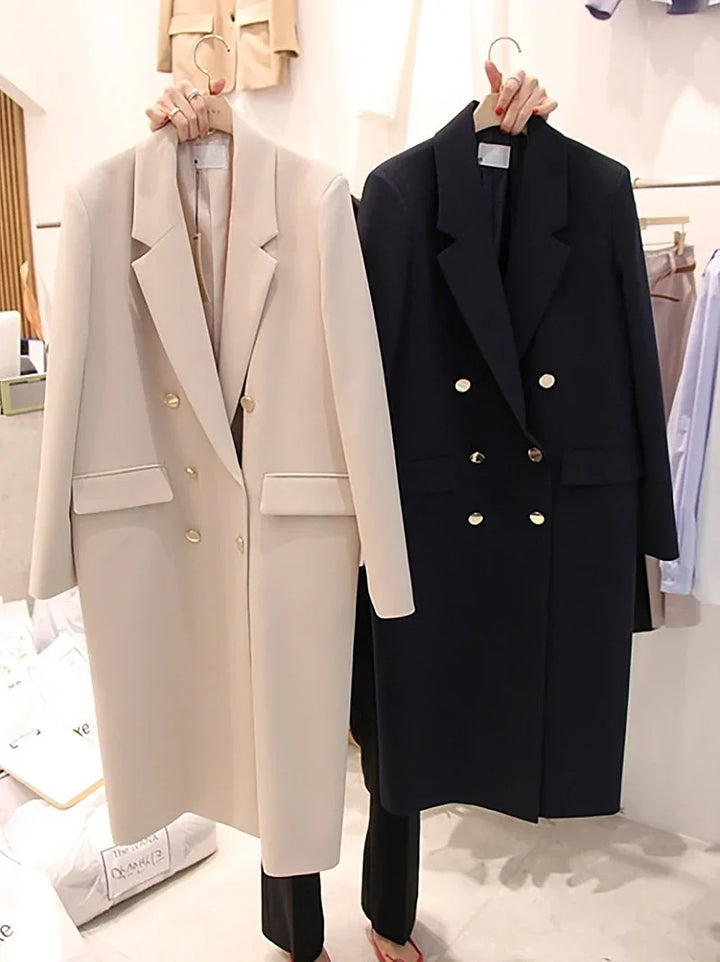 Beige and black double-breasted long coats with gold buttons on hangers in a clothing store