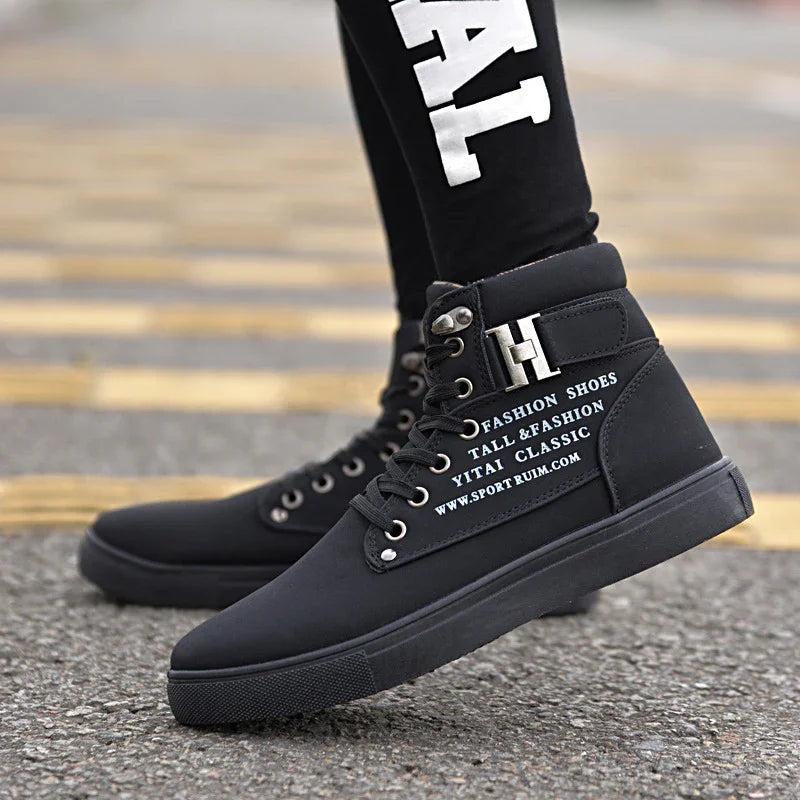Black high-top fashion sneakers with white text and metal accents on urban pavement