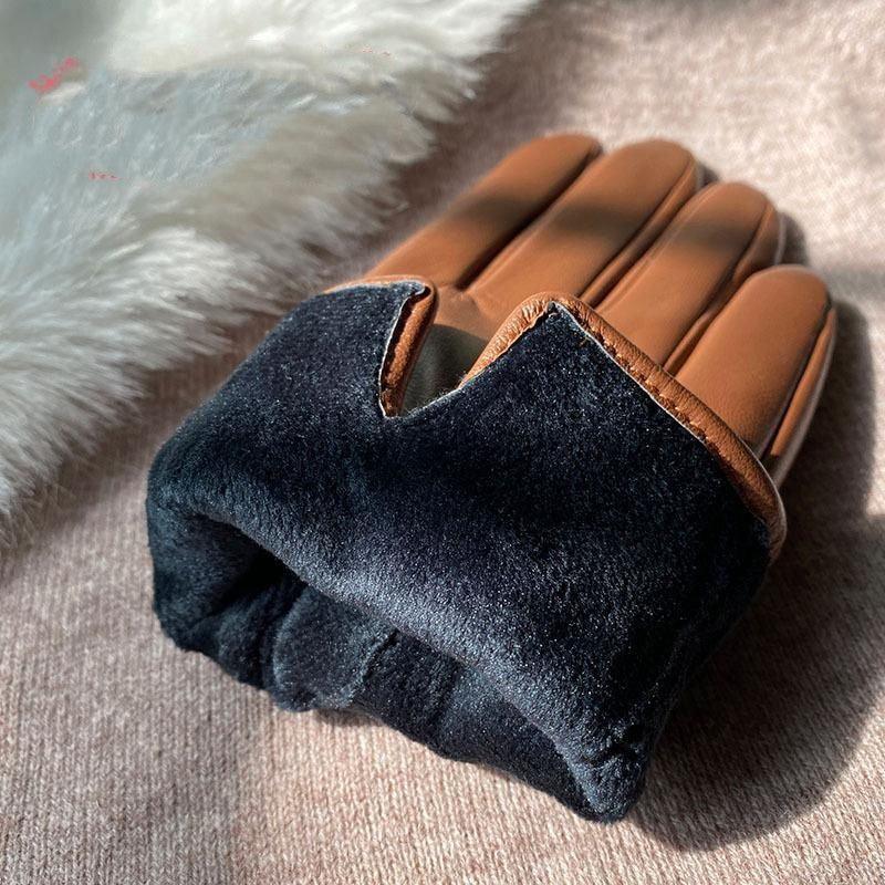 Brown leather gloves with black fleece lining on beige fabric background, close-up winter accessory