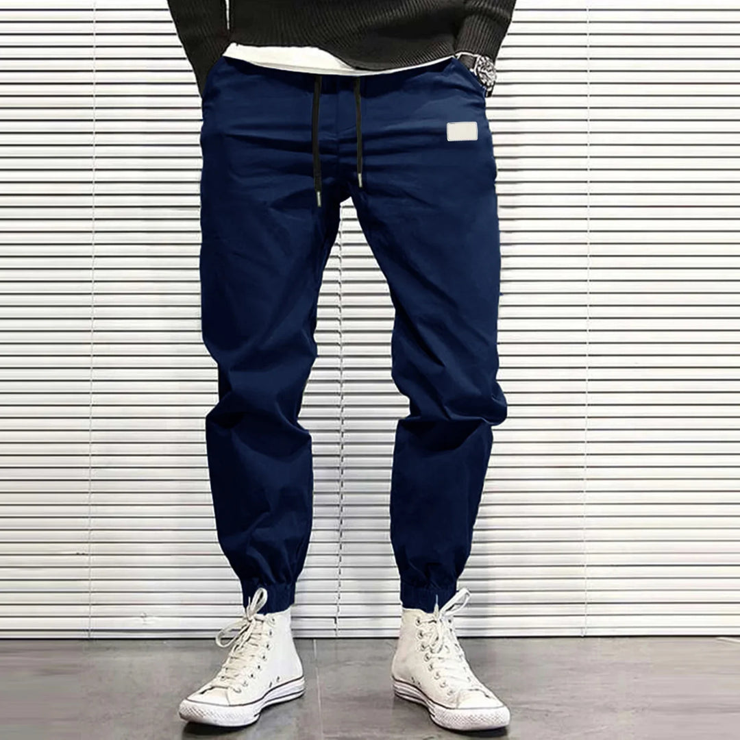 Man wearing navy blue jogger pants with elastic cuffs and white high-top sneakers