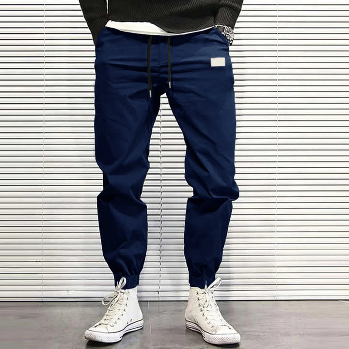 Man wearing navy blue jogger pants with elastic cuffs and white high-top sneakers