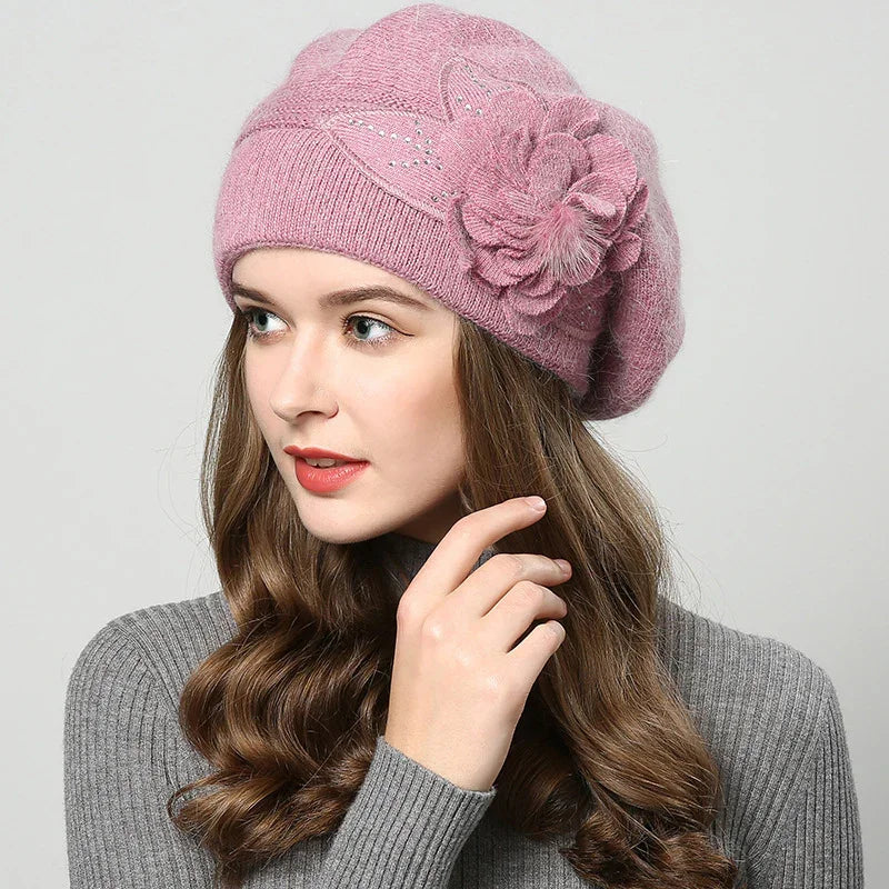 Young woman wearing pink knitted beret with floral design and grey ribbed sweater