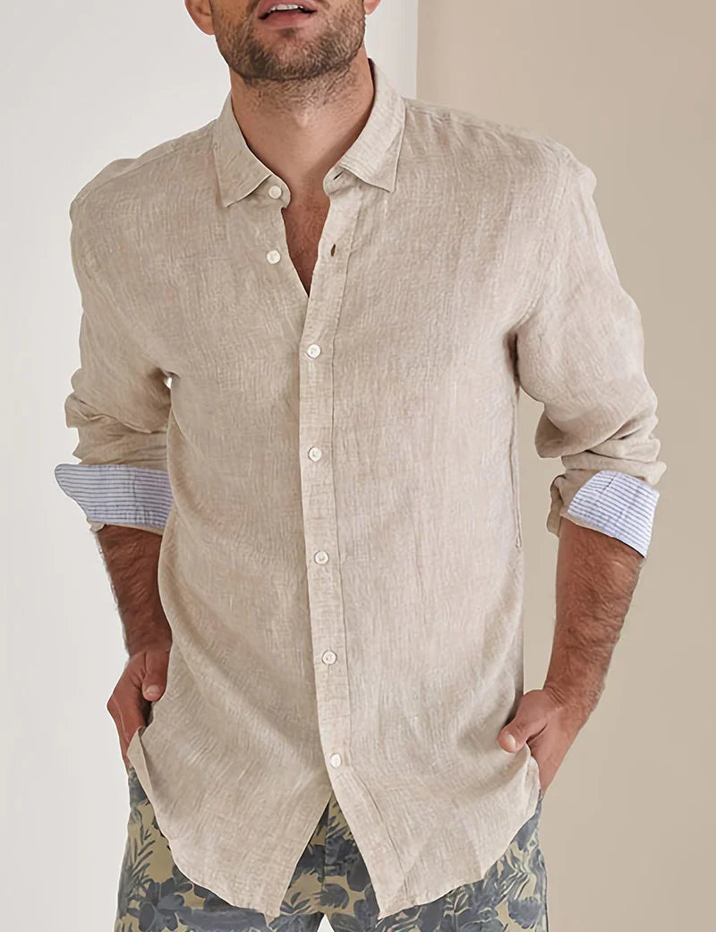 Man wearing beige linen button-up shirt with rolled sleeves and floral patterned shorts