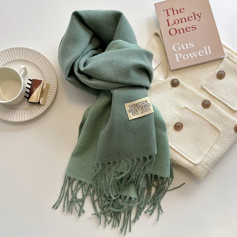 Green fringed wool scarf with Undreson label, cream cardigan with brown buttons, book The Lonely Ones by Gus Powell, white cup and saucer with hair clips