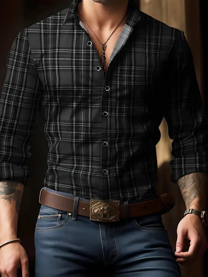 Man wearing black plaid button-up shirt with rolled sleeves, brown belt with ornate buckle, blue jeans, and accessories