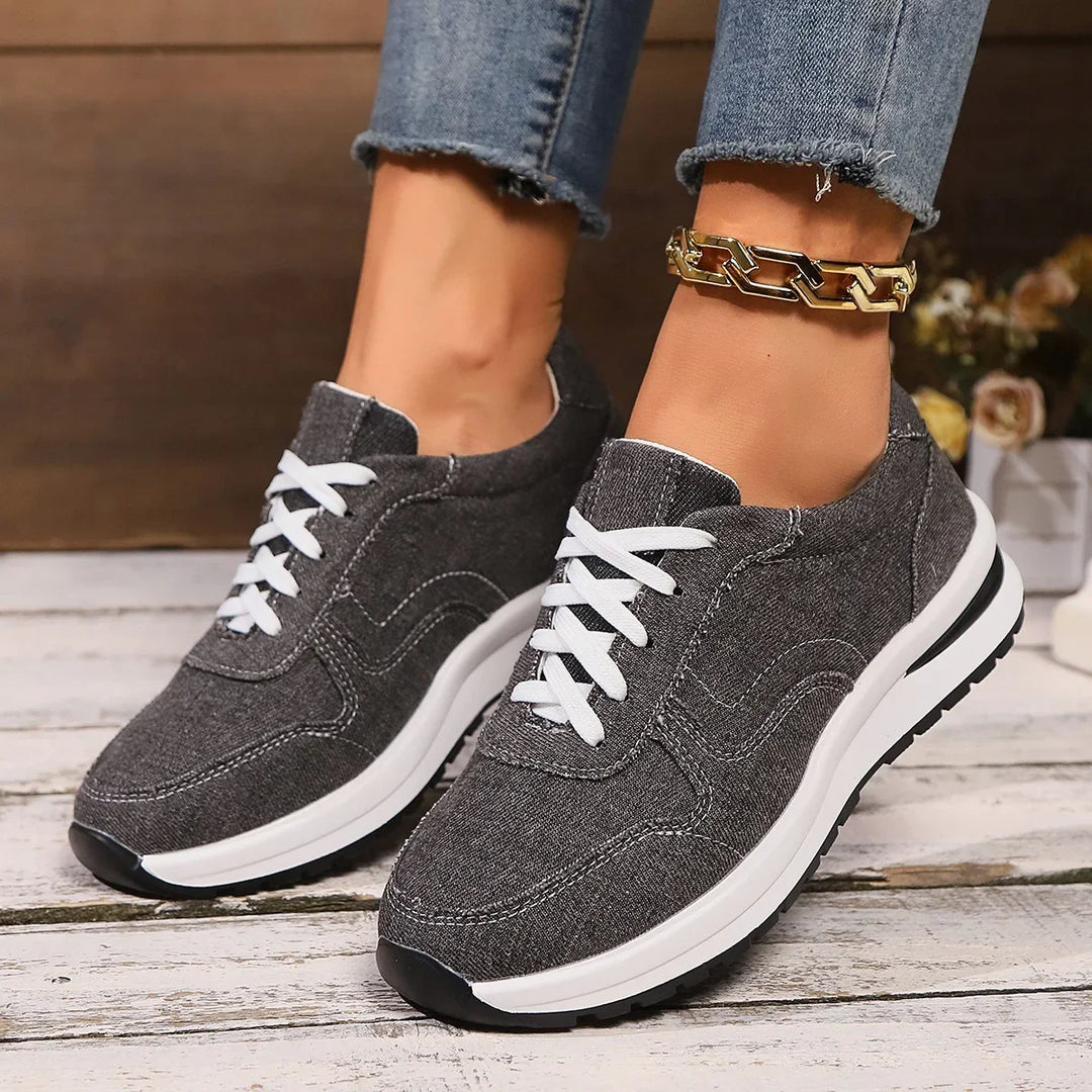 Gray casual sneakers with white laces worn with frayed hem jeans and gold chain anklet