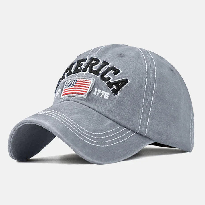 Gray baseball cap with white stitching, embroidered American flag, and text AMERICA 1776
