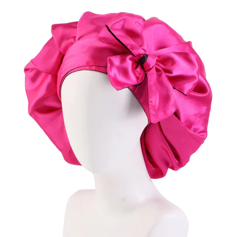 Bright pink satin bonnet with large decorative bow on white mannequin head