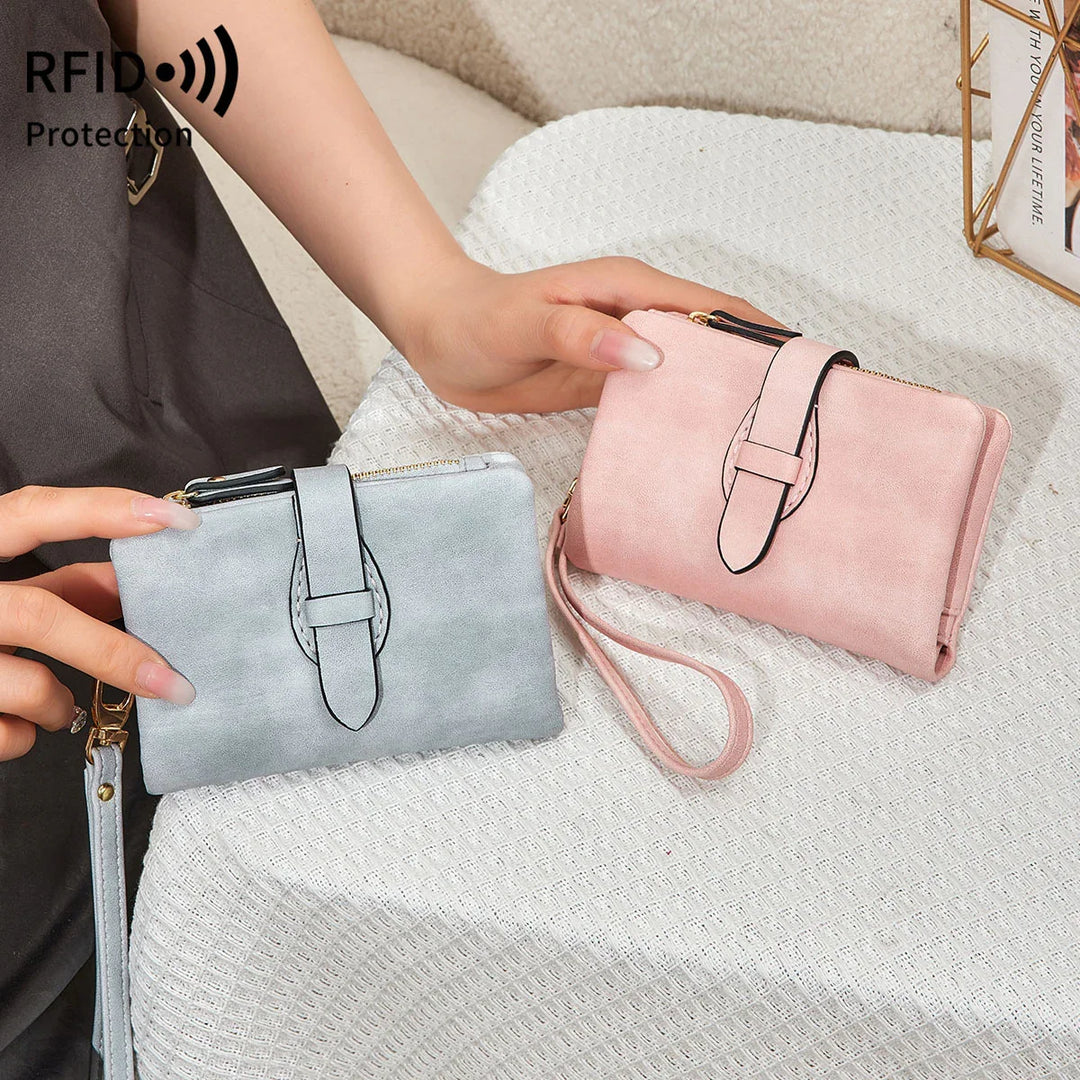 Two RFID protection wristlet wallets in gray and pink suede on textured white tablecloth