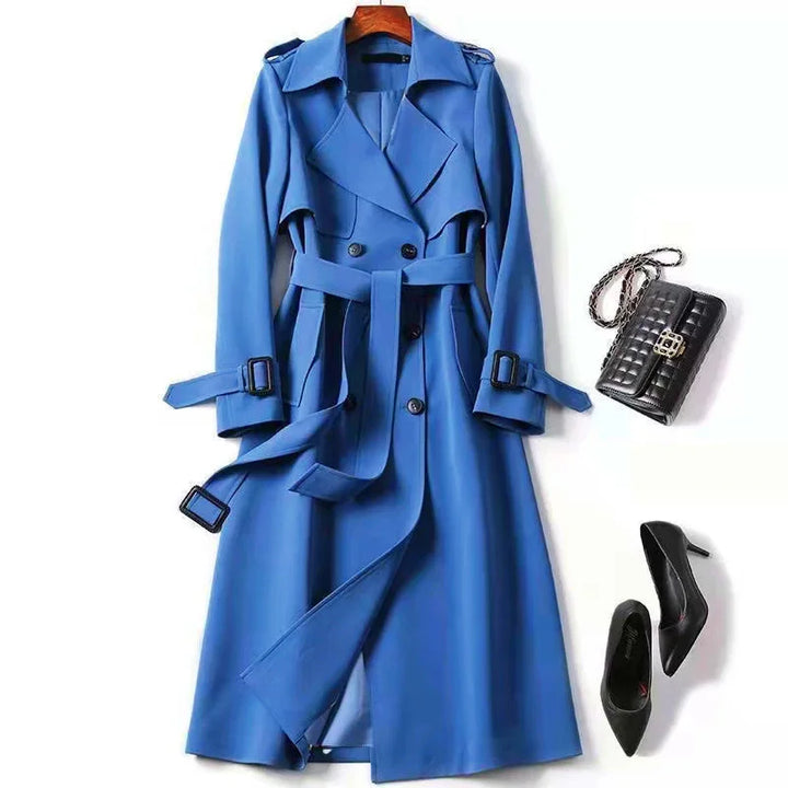 Blue double-breasted trench coat with belt, paired with black quilted handbag and black high heels