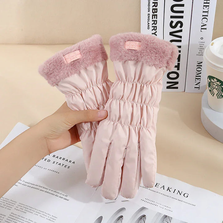 Pink winter gloves with fluffy cuffs, held above a newspaper and near Starbucks cup