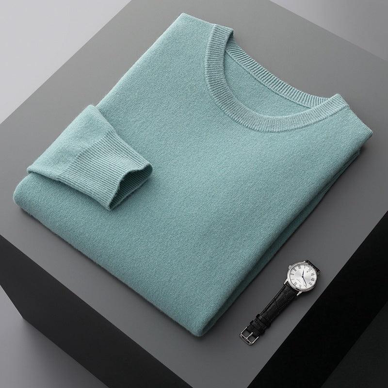Folded light blue knit sweater with a black leather wristwatch on a gray surface