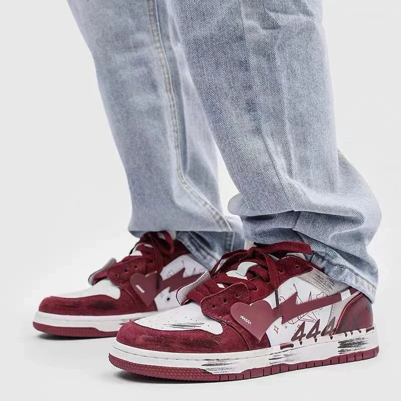 Close-up of red and white low-top sneakers with graffiti details and number 444, worn with light blue jeans