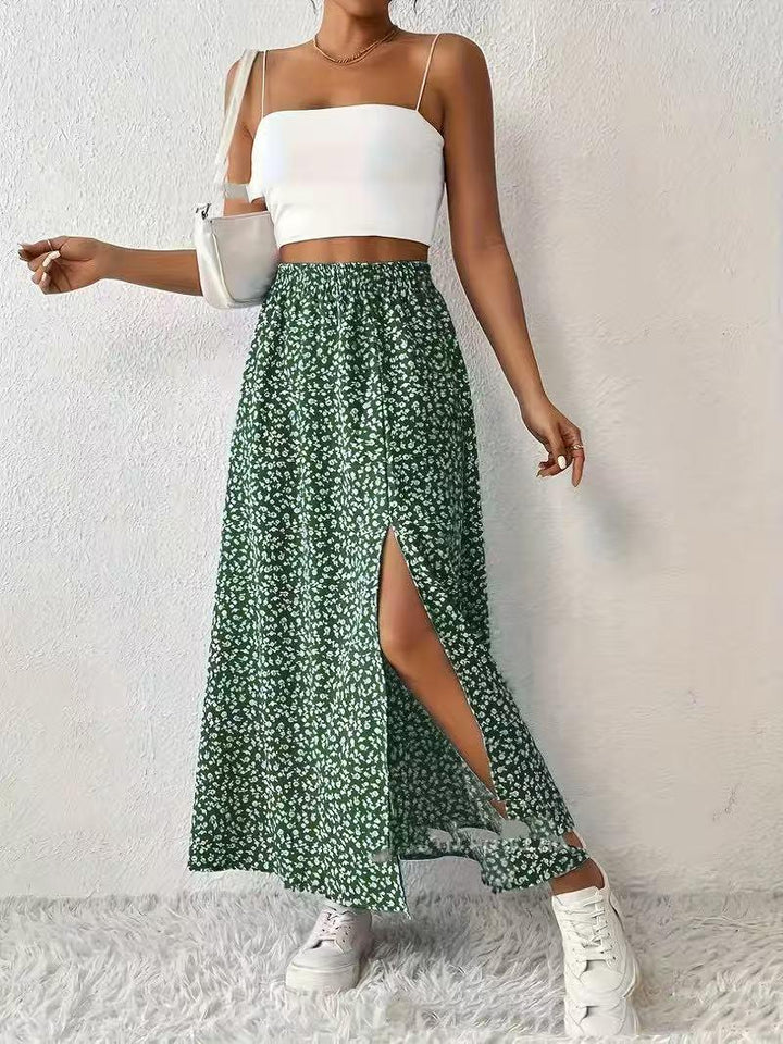 Woman wearing white crop top, green floral slit maxi skirt, white sneakers, and white shoulder bag
